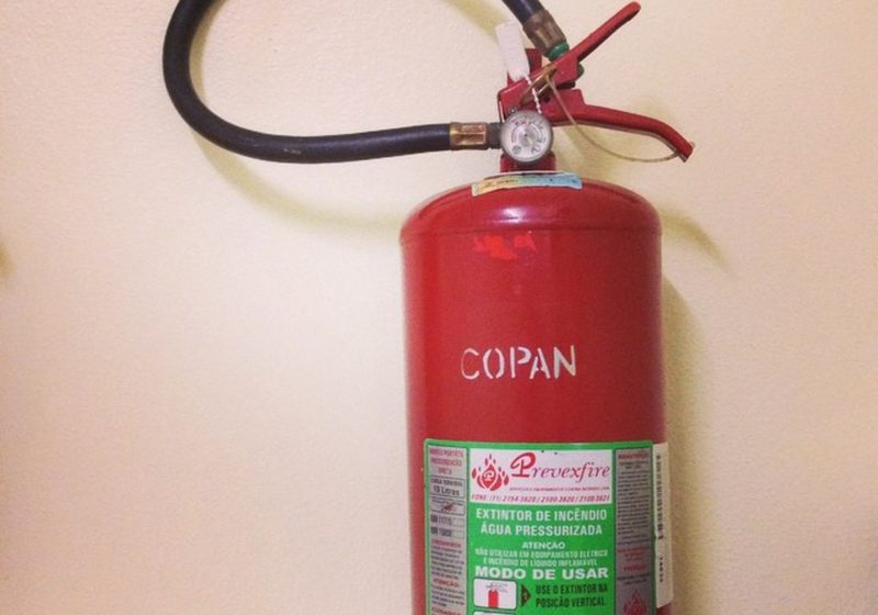 A red fire extinguisher mounted on a pale wall